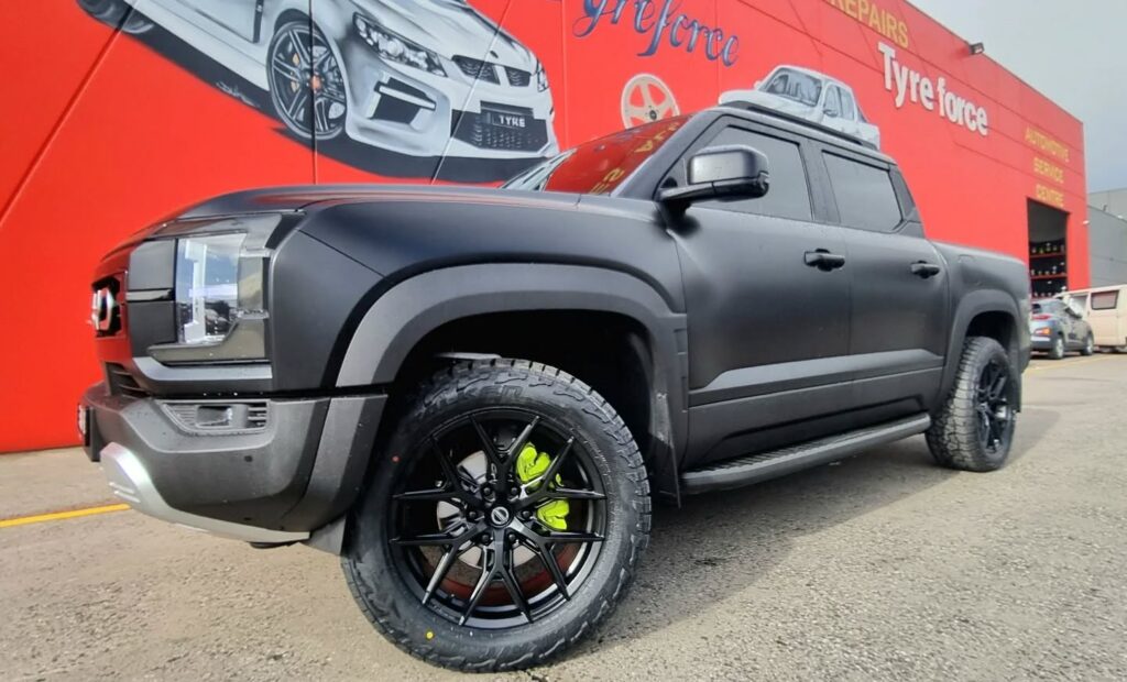 Dark BYD Shark ute with GT Form GFS1 matte black wheels and all-terrain tyres outside Tyreforce.