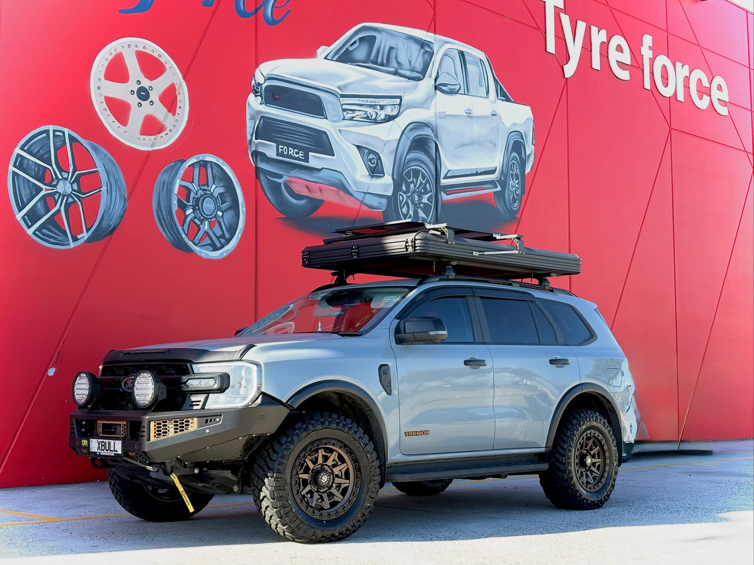Silver Ford Everest with bronze alloy wheels and off-road tyres outside Tyreforce.
