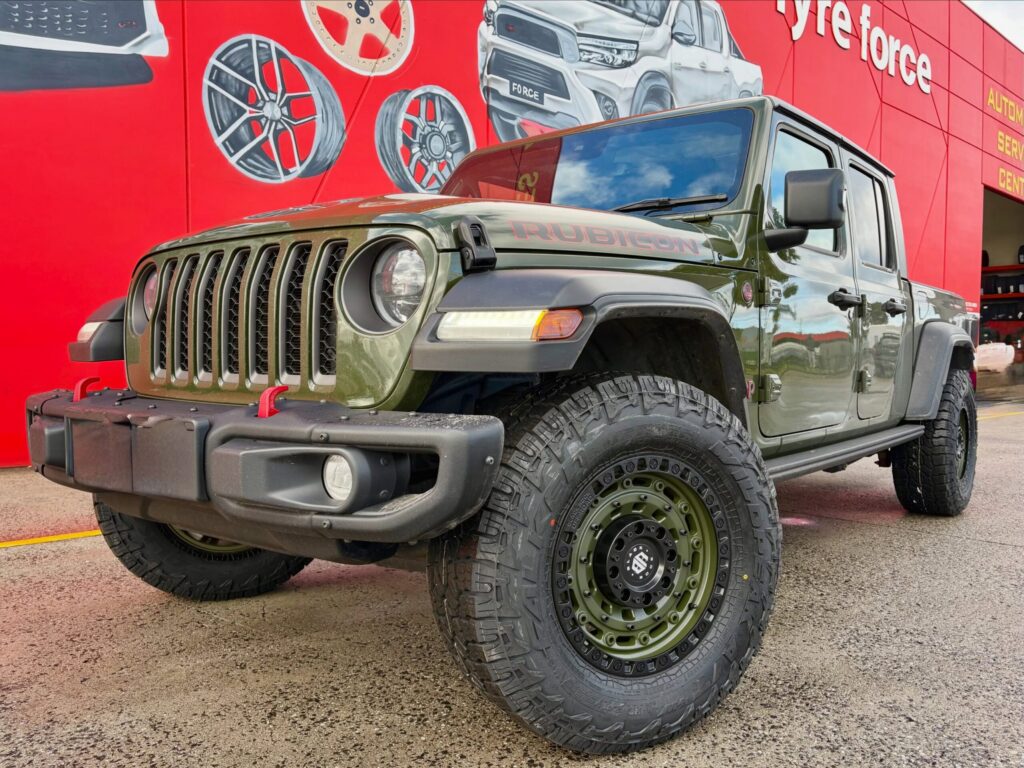 Green Jeep Gladiator Rubicon with matching green alloy wheels and off-road tyres outside Tyreforce.