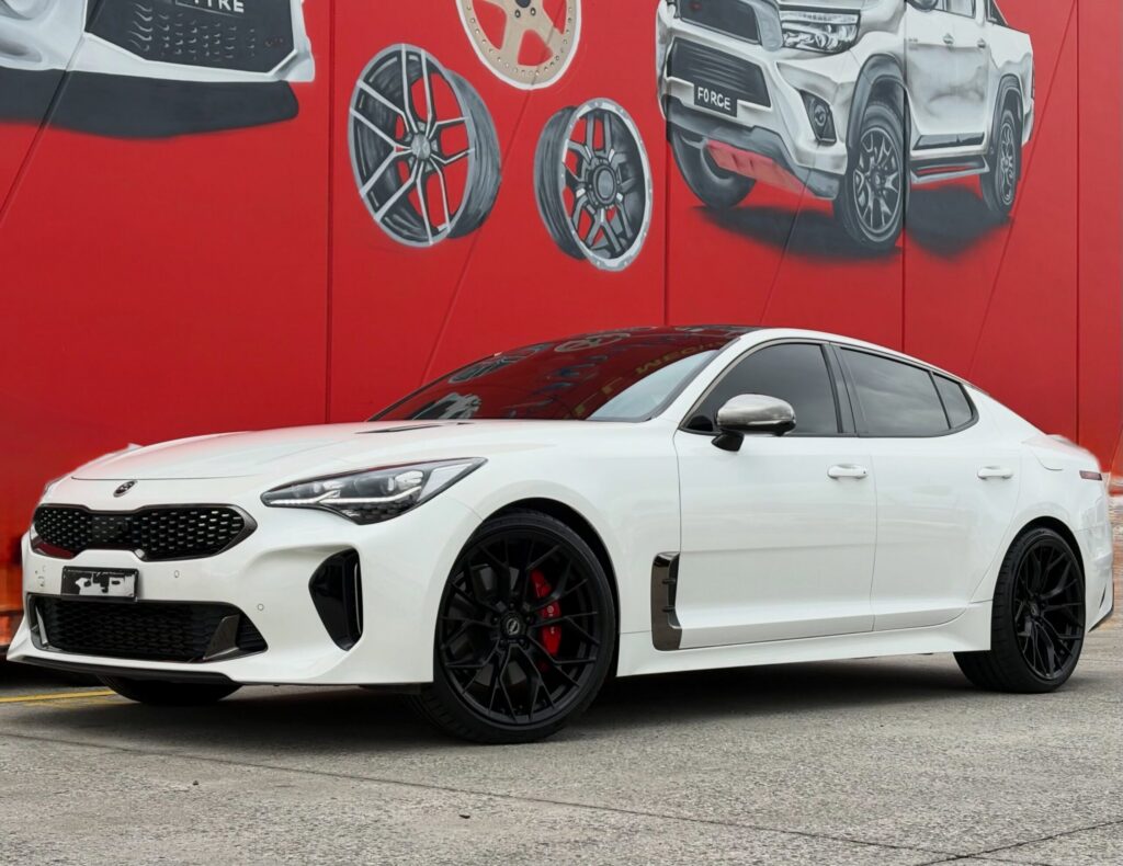 White Kia Stinger with black multi-spoke alloy wheels outside Tyreforce.