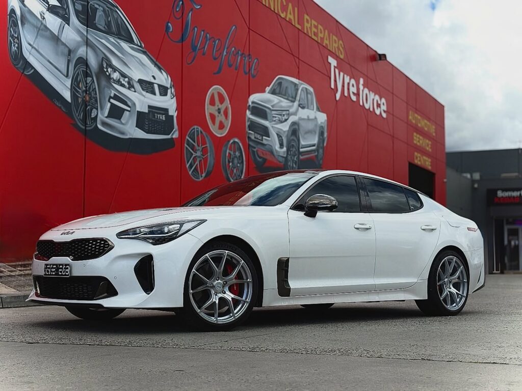 White Kia Stinger with silver multi-spoke alloy wheels and red brake calipers outside Tyreforce.