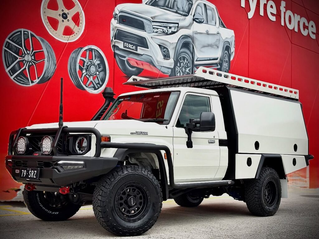 White Toyota LandCruiser 79 Series ute with black wheels and off-road tyres outside Tyreforce.